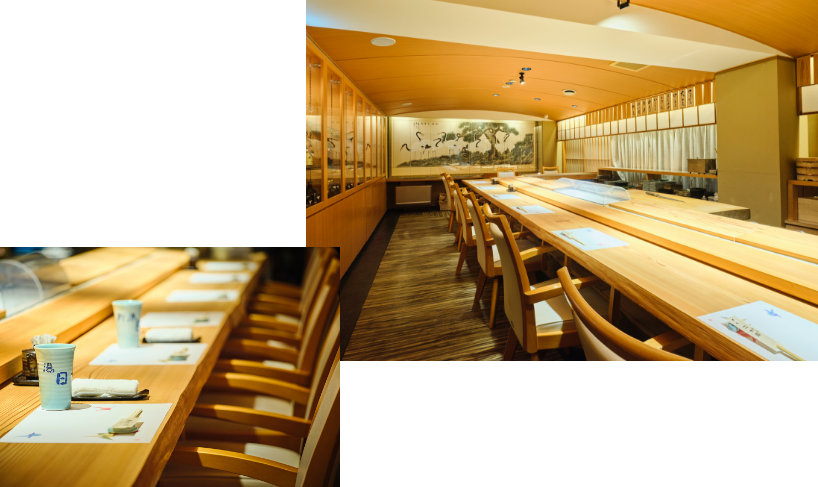 Counter seats at a sushi restaurant decorated in Japanese style. Chairs lined up at the wooden counter with prepared chopsticks and teacups can be seen.