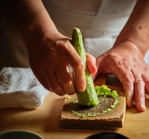 A craftsman grates wasabi with a sharkskin grater.