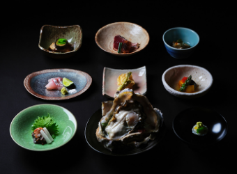 Sashimi and assorted sashimi on small colorful plates arranged on a black table.