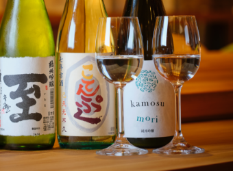 Five bottles and two wine glasses lined up on the counter.