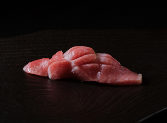 Nigirizushi of fresh chutoro (medium fatty tuna) served on a black plate.